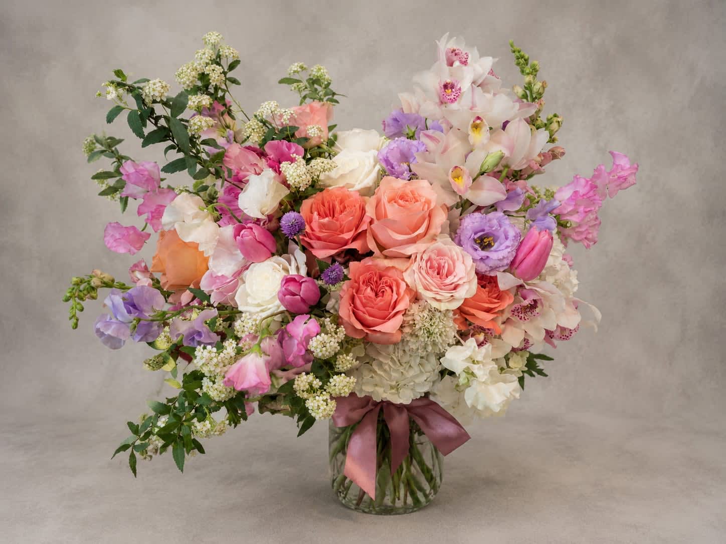 Spring Reverie - Inspired by the beauty of spring in full bloom, this luxurious arrangement showcases garden roses, sweet peas, orchids, tulips, hydrangea, and seasonal accents. Designed with movement and abundance, Spring Reverie is a stunning gift for life's most memorable moments.