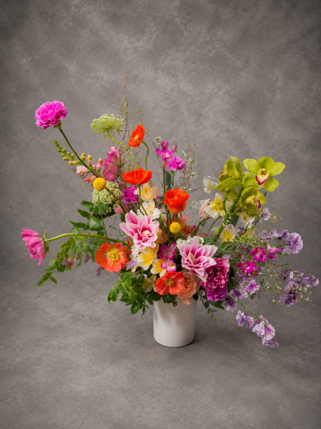 Wild Bloom - Bursting with movement, color, and seasonal beauty, Wild Bloom features an artistic blend of poppies, sweet peas, orchids, garden roses, and premium seasonal flowers. Designed in a loose garden style, this arrangement celebrates the natural beauty and spontaneity of flowers in bloom.
