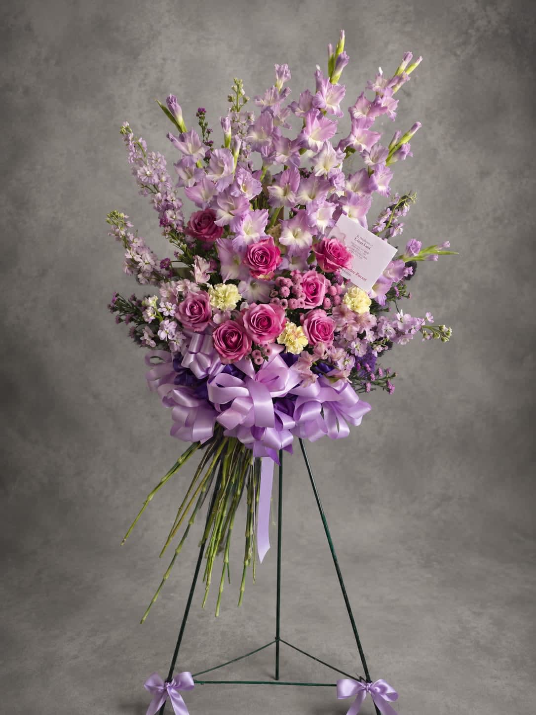 Fields of Grace - Lavender gladiolus rise above roses, stock, and seasonal blooms in this timeless standing spray. Designed with beauty and dignity, Fields of Grace offers a thoughtful tribute to honor a life well lived.