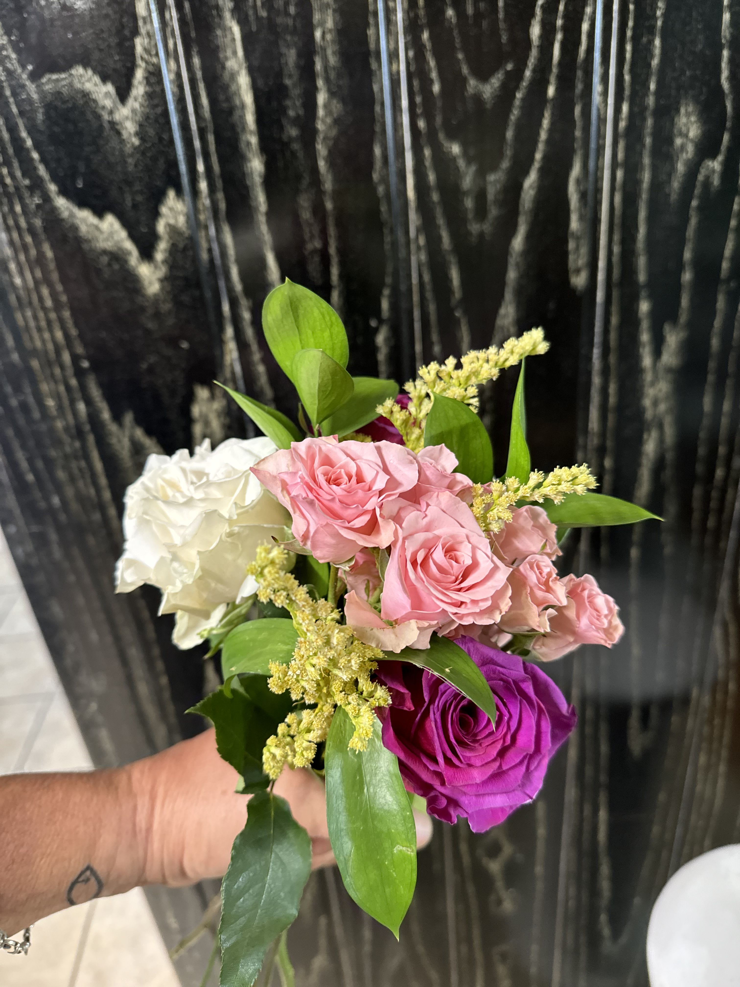 Small hand-tied bouquet of pink, white, and purple roses