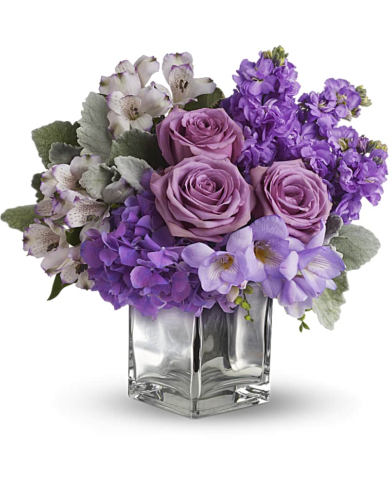 Purple roses and mixed lavender flowers in a clear glass vase
