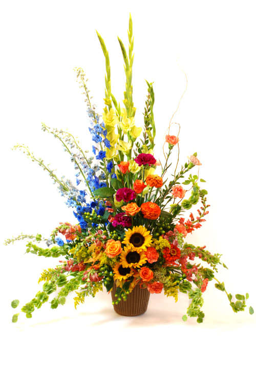 Tall mixed flower arrangement in a brown vase with sunflowers and bright blooms