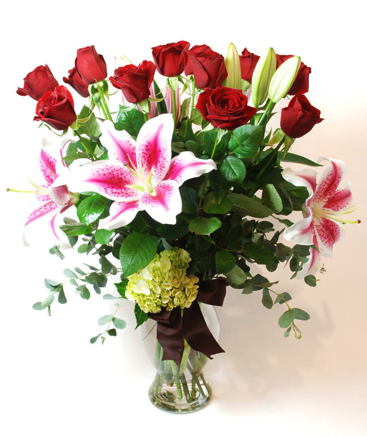 Bouquet of red roses and pink lilies in a clear glass vase