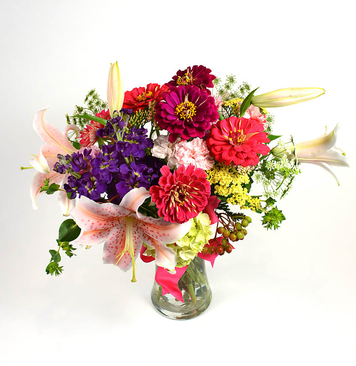 Colorful bouquet of zinnias and lilies in a glass vase