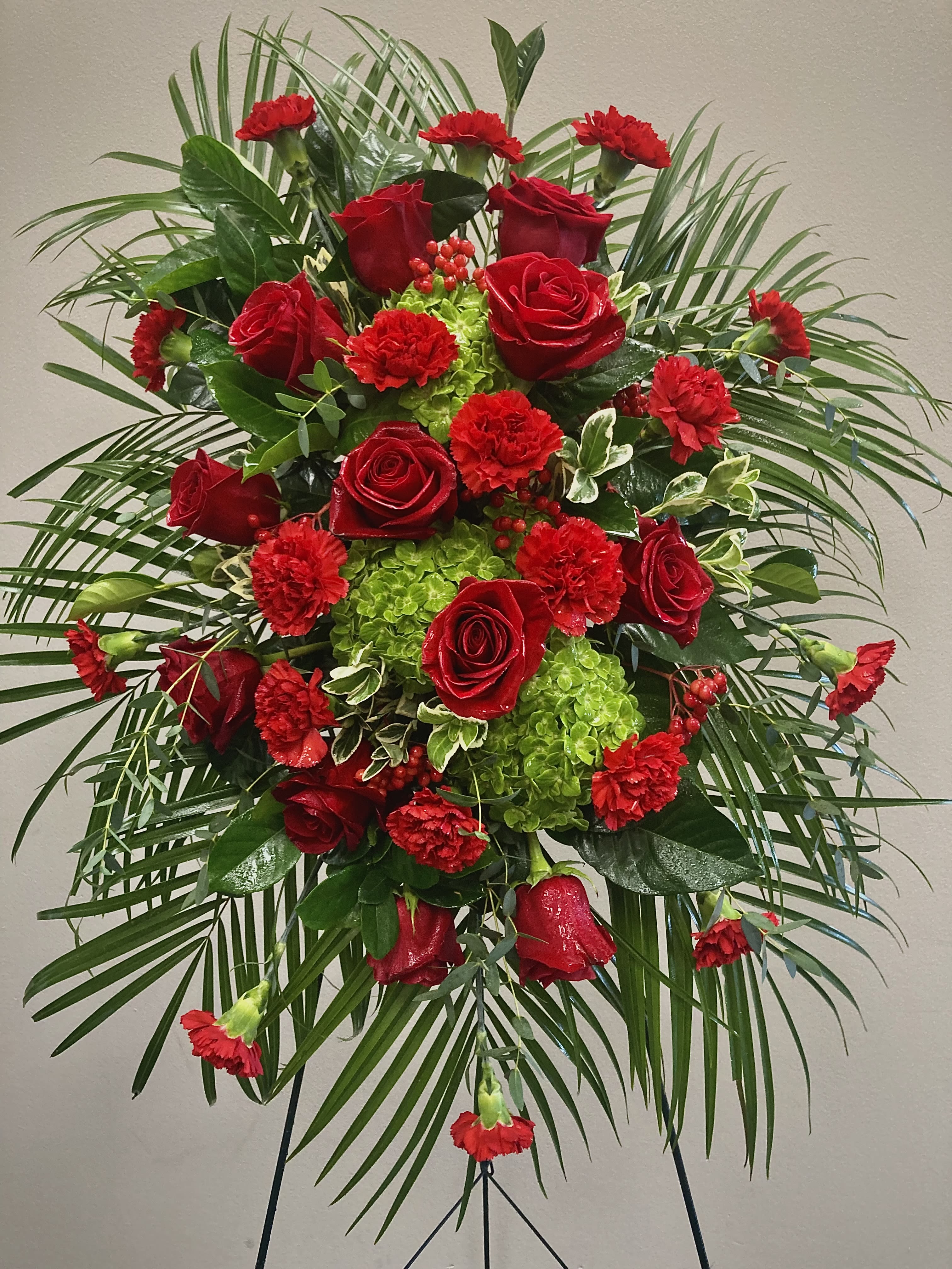 Standing floral spray with red roses and carnations on a tripod easel
