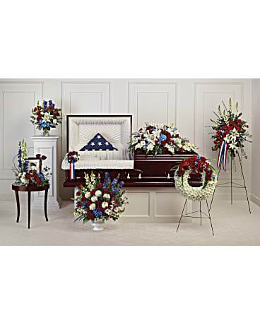 Funeral casket surrounded by red, white, and blue floral sprays