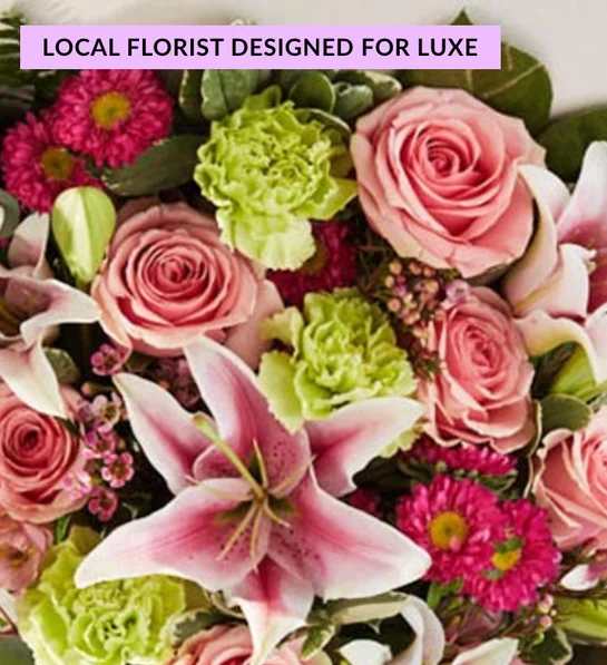 Pink roses and a pink lily with bright green carnations and magenta daisies