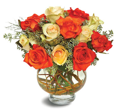 Round arrangement of orange and cream roses in a clear glass bowl vase