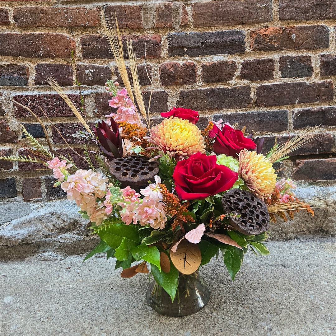Mixed bouquet of red roses and pale pink flowers in a glass vase