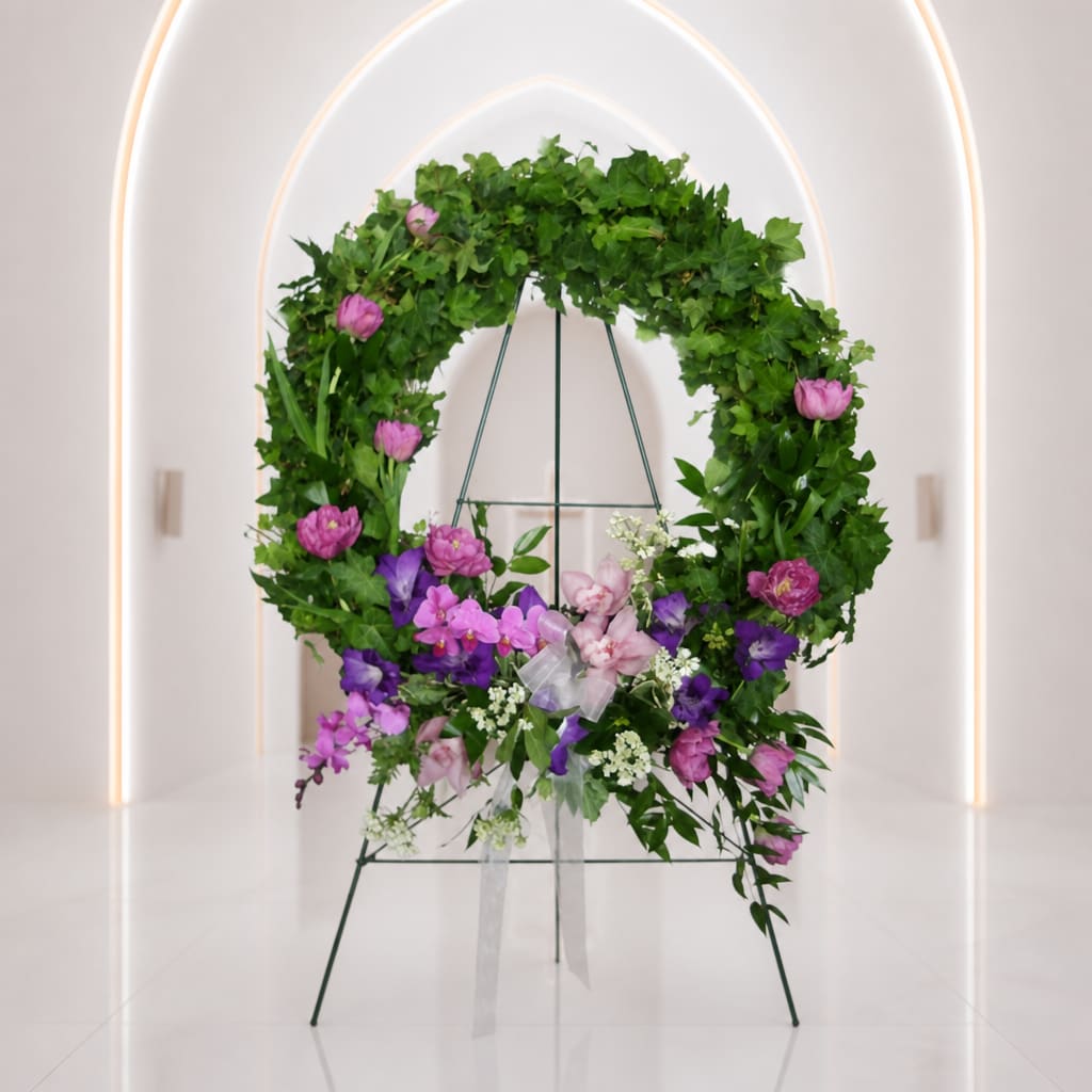 Circular floral wreath on a stand with pink and purple flowers