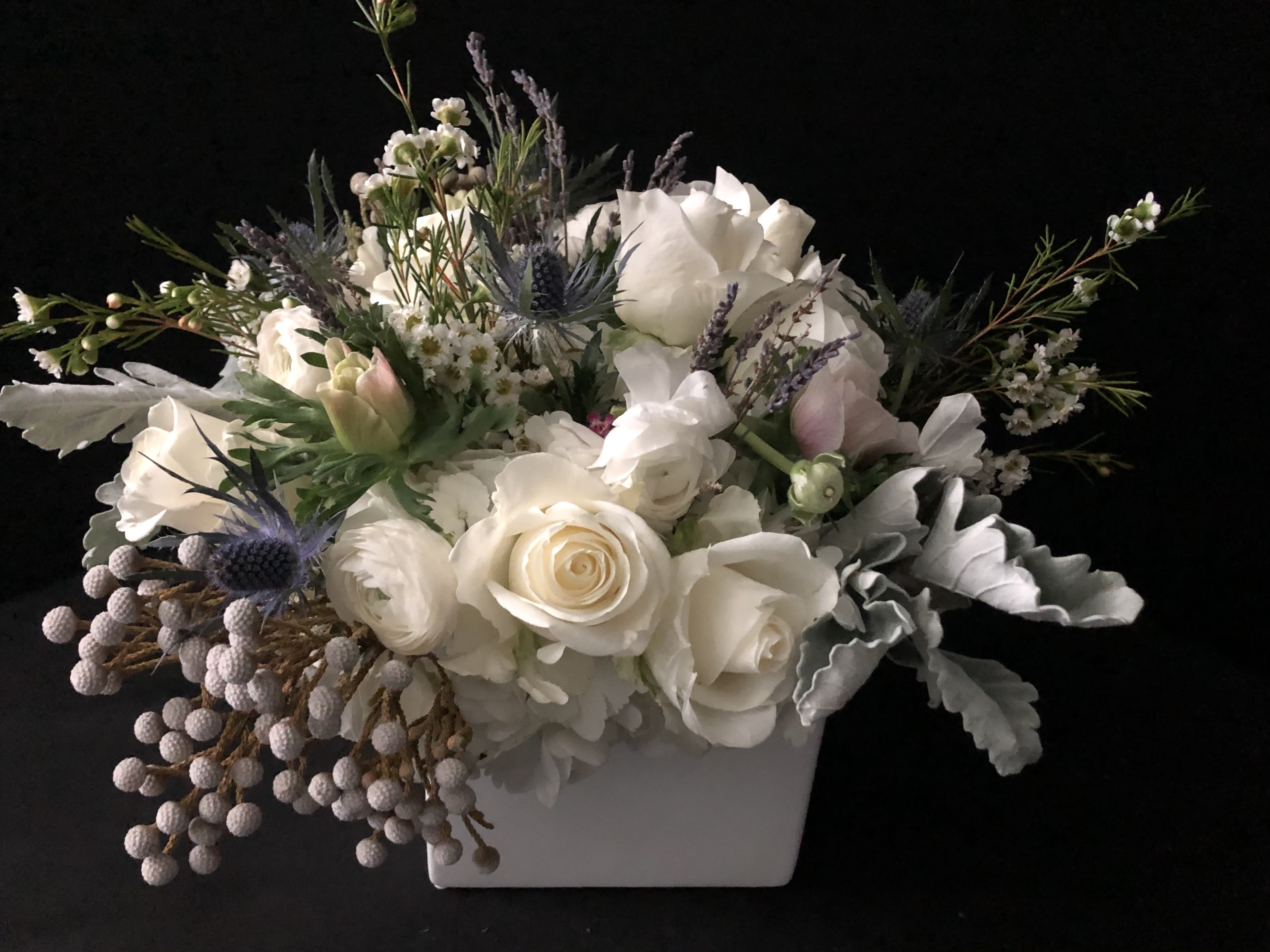 White rose arrangement in a white rectangular vase with lavender accents