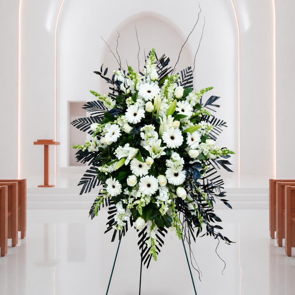 White floral standing spray with lilies and daisies on an easel
