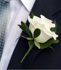 White rose boutonniere on a dark suit jacket