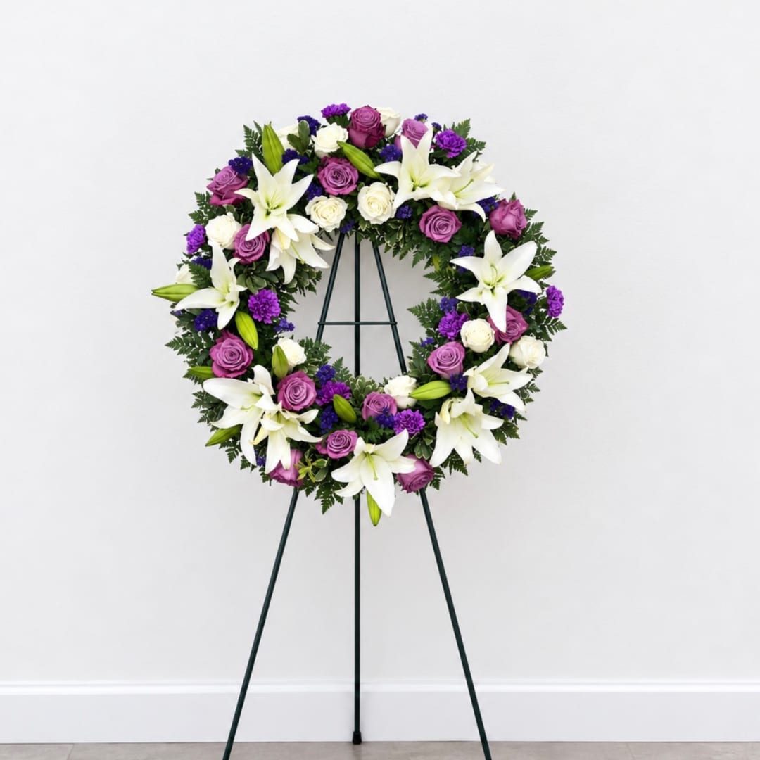Purple and white floral wreath on a black easel stand