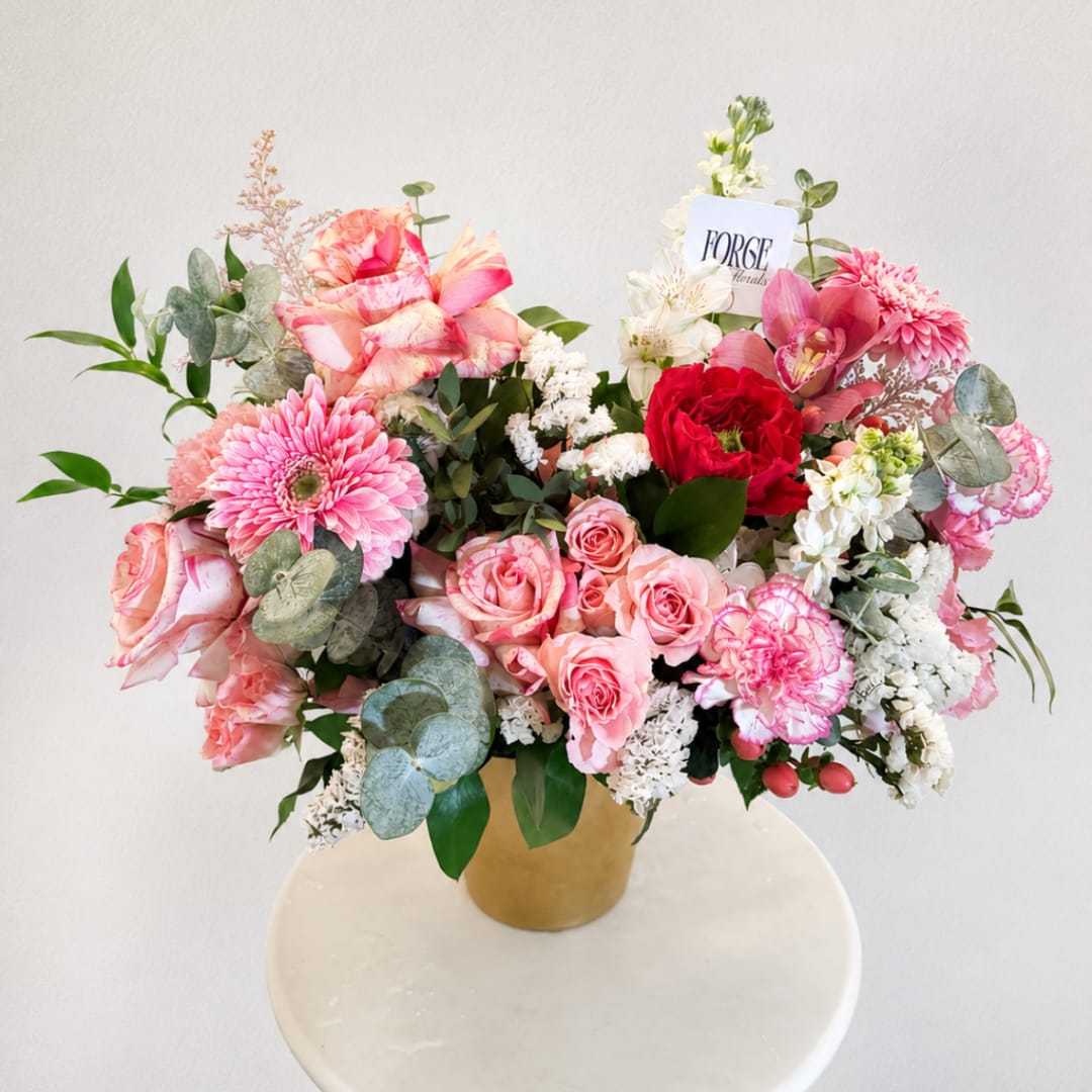 Pink and white mixed flower arrangement in a gold vase
