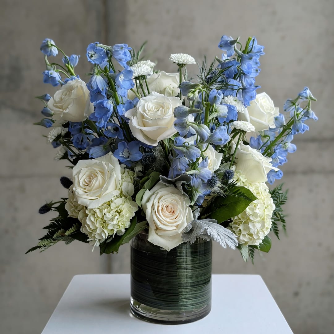 White roses and blue delphinium in a glass vase