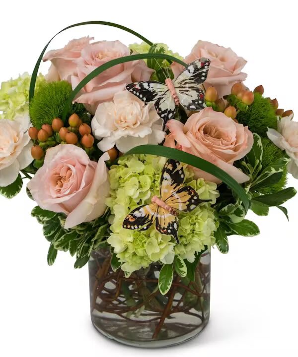 Pink roses and green hydrangeas in a glass vase with butterfly accents