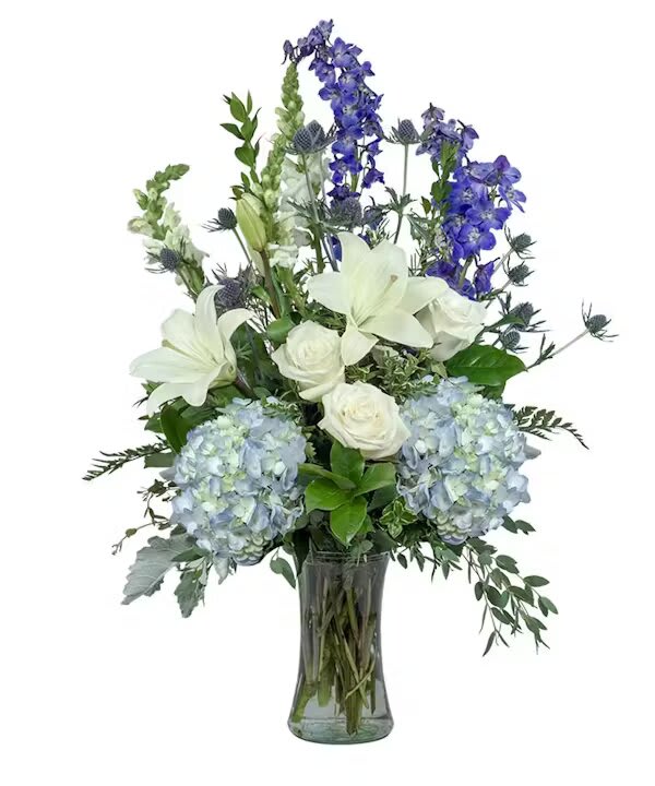 Blue hydrangeas, white lilies, and roses in a glass vase