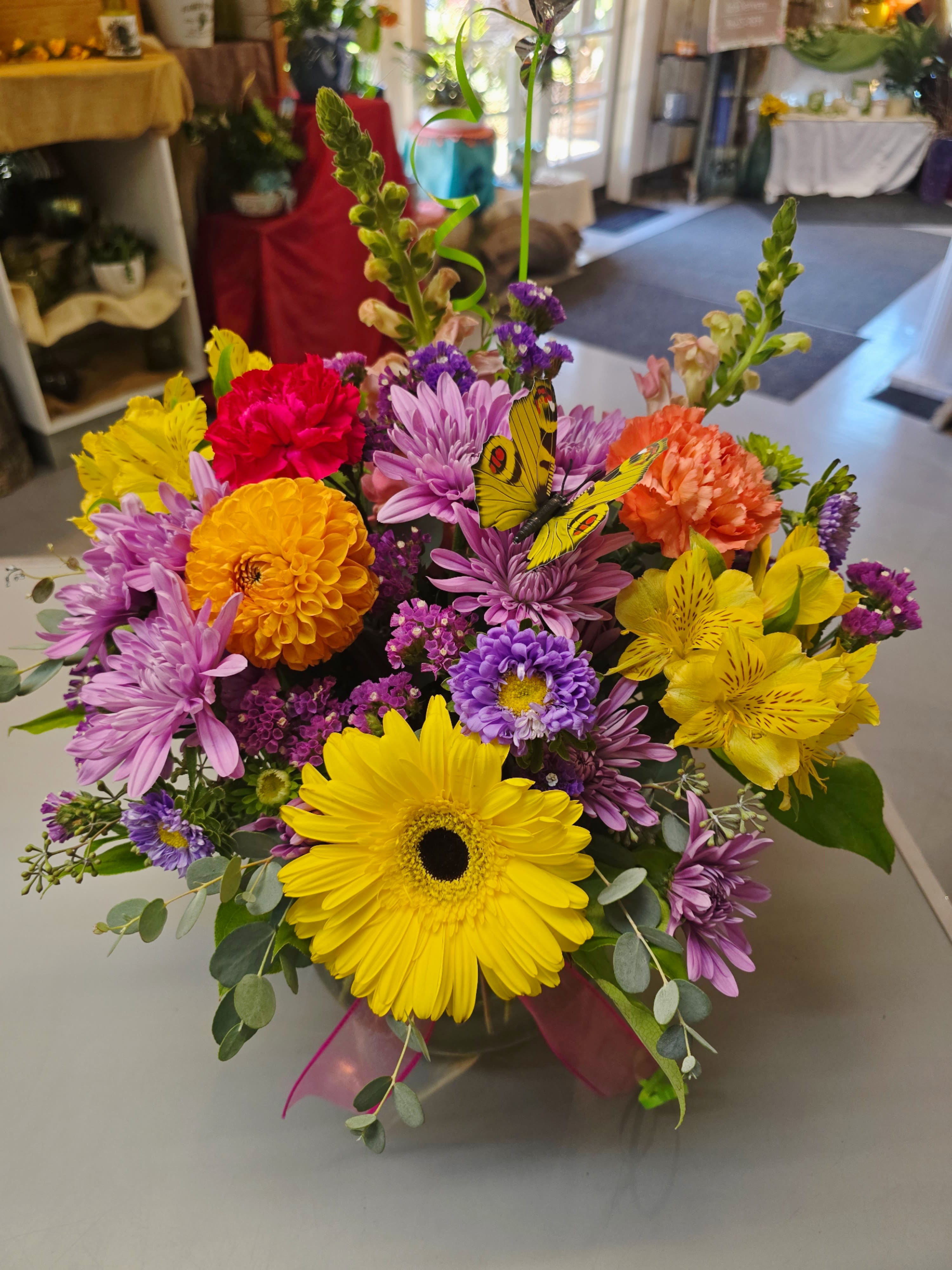 Bright mixed bouquet with gerbera daisies, chrysanthemums, and a butterfly pick