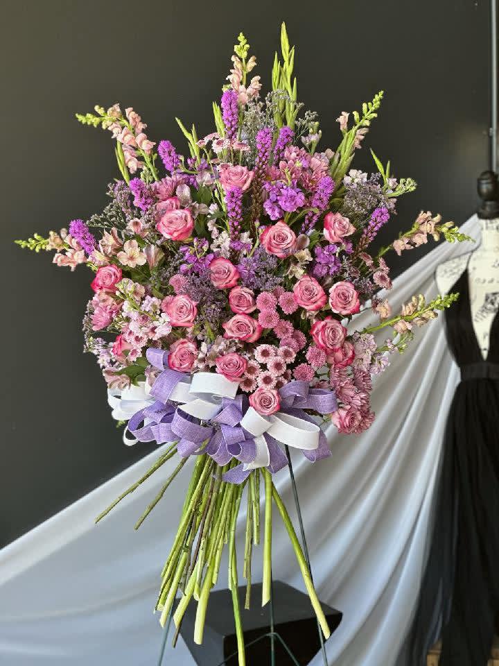 Large bouquet of pink and purple flowers tied with lavender and white ribbons