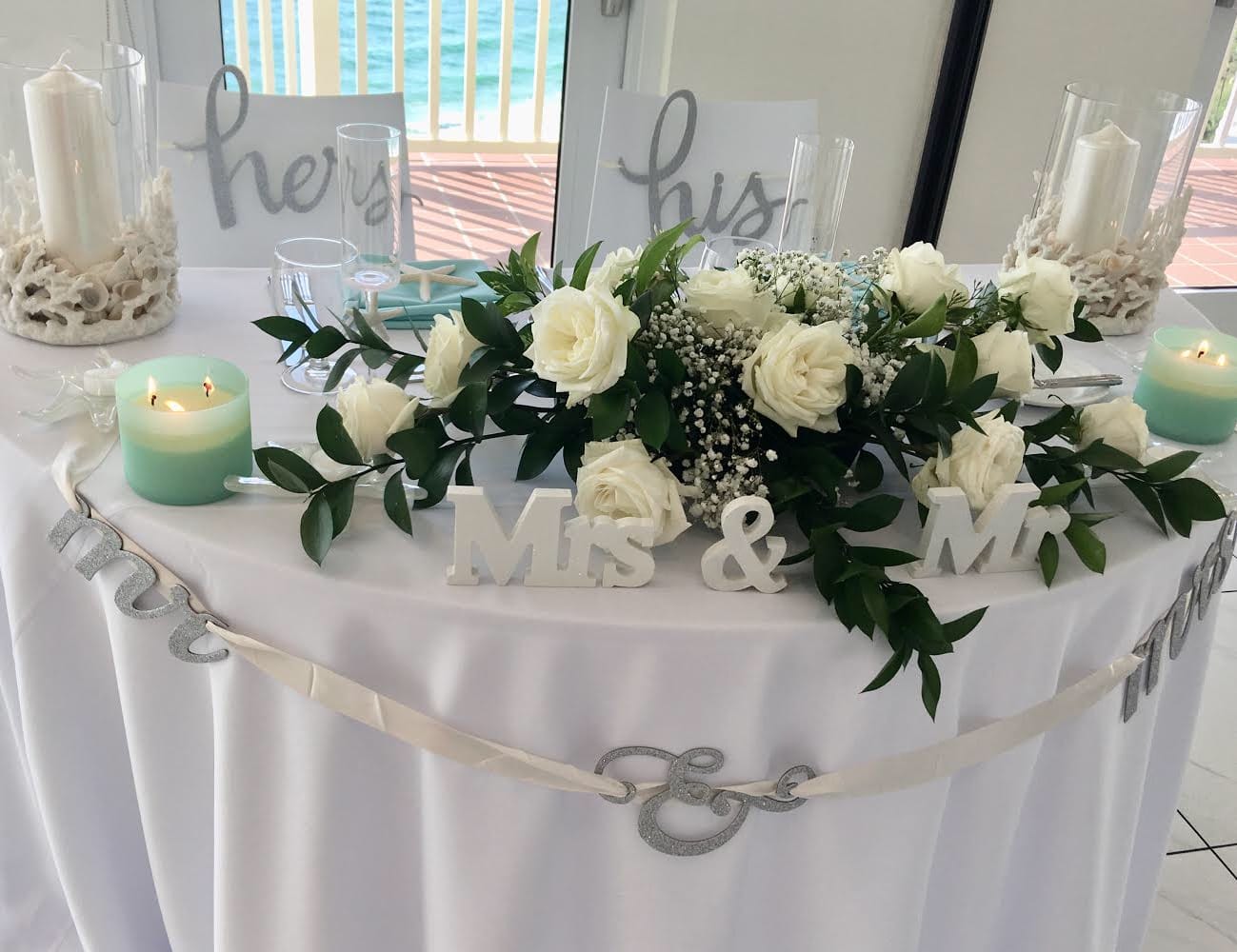 White rose centerpiece on a decorated wedding table with candles