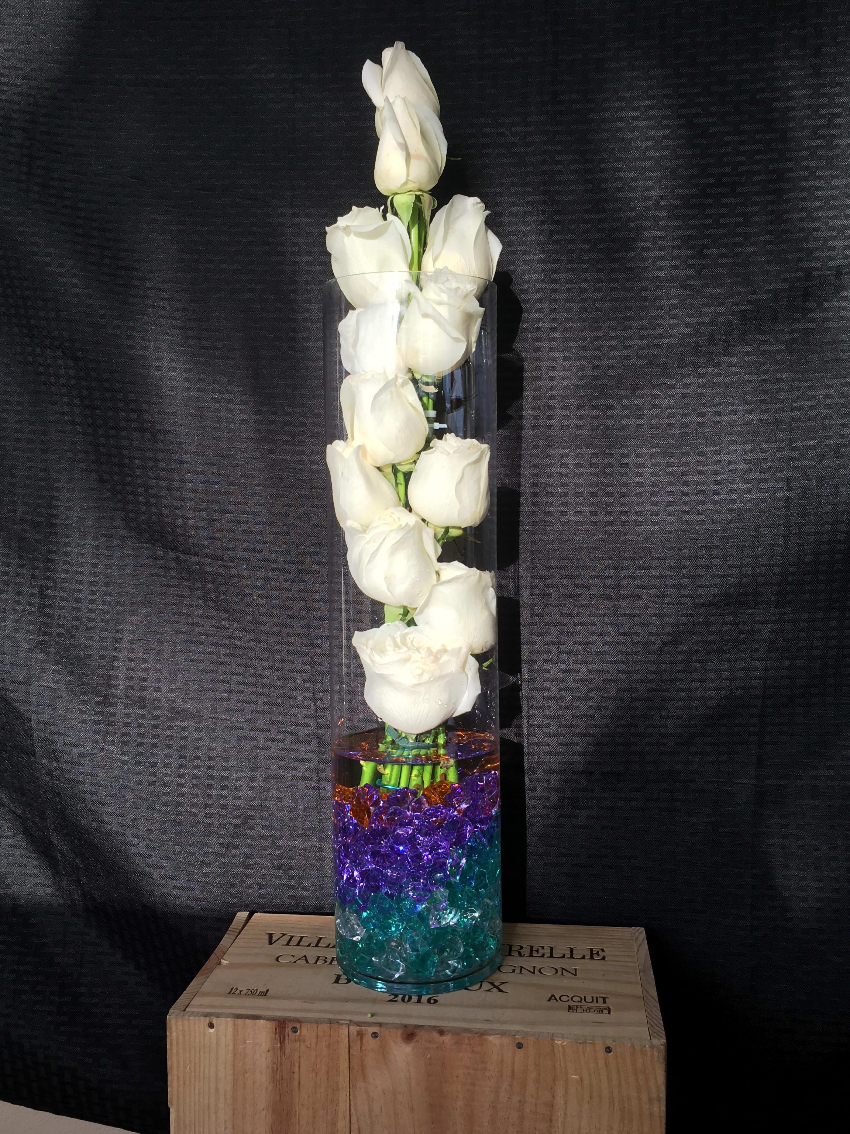 Deluxe Diamonds - White Roses with color acrylic Gems in tall cylinder glass vase 