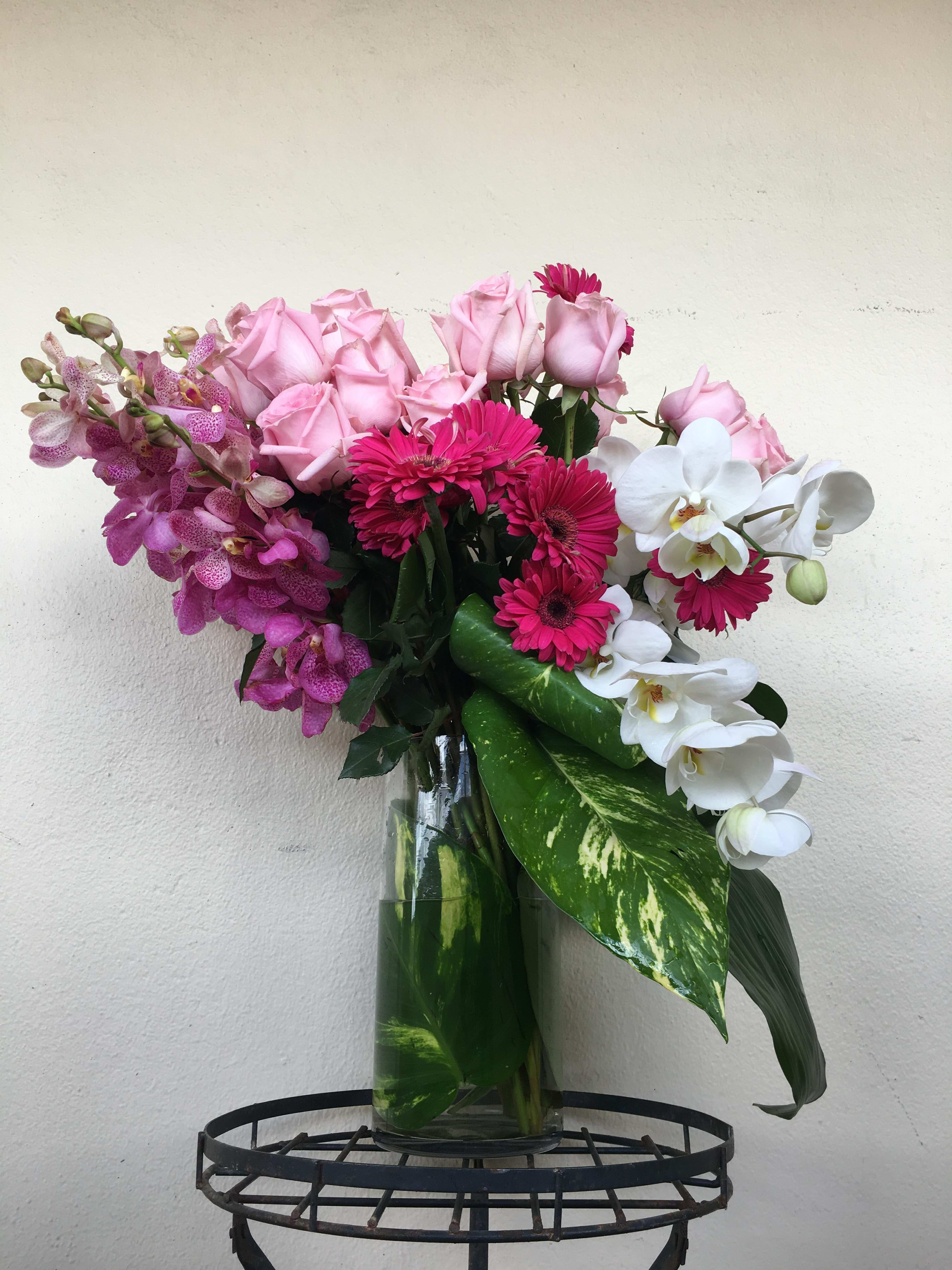 Pink Monet  - Orchid blooms , Roses ,green in tall cylinder glass vase 