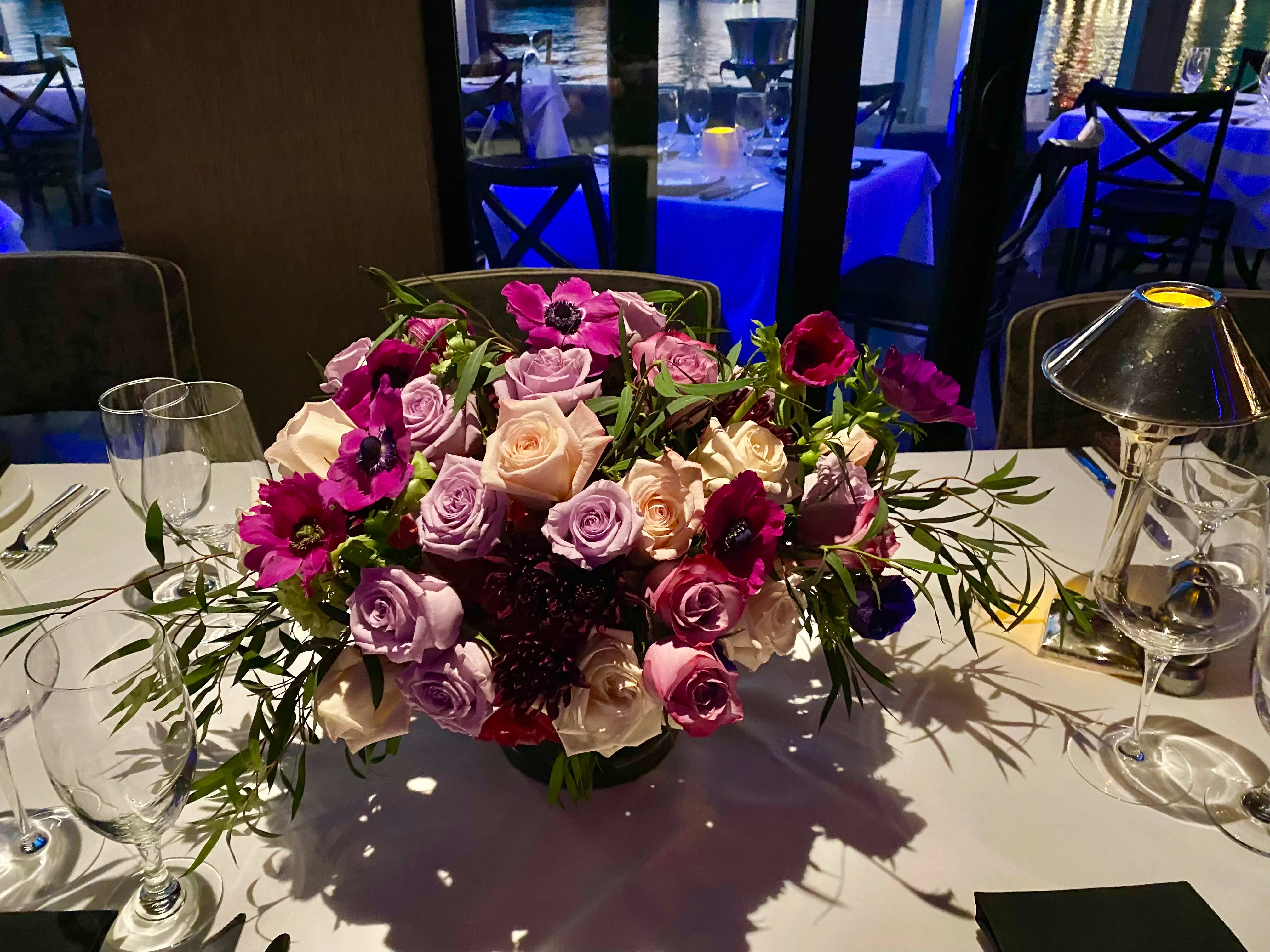 Low centerpiece of pink and lavender roses on a dining table