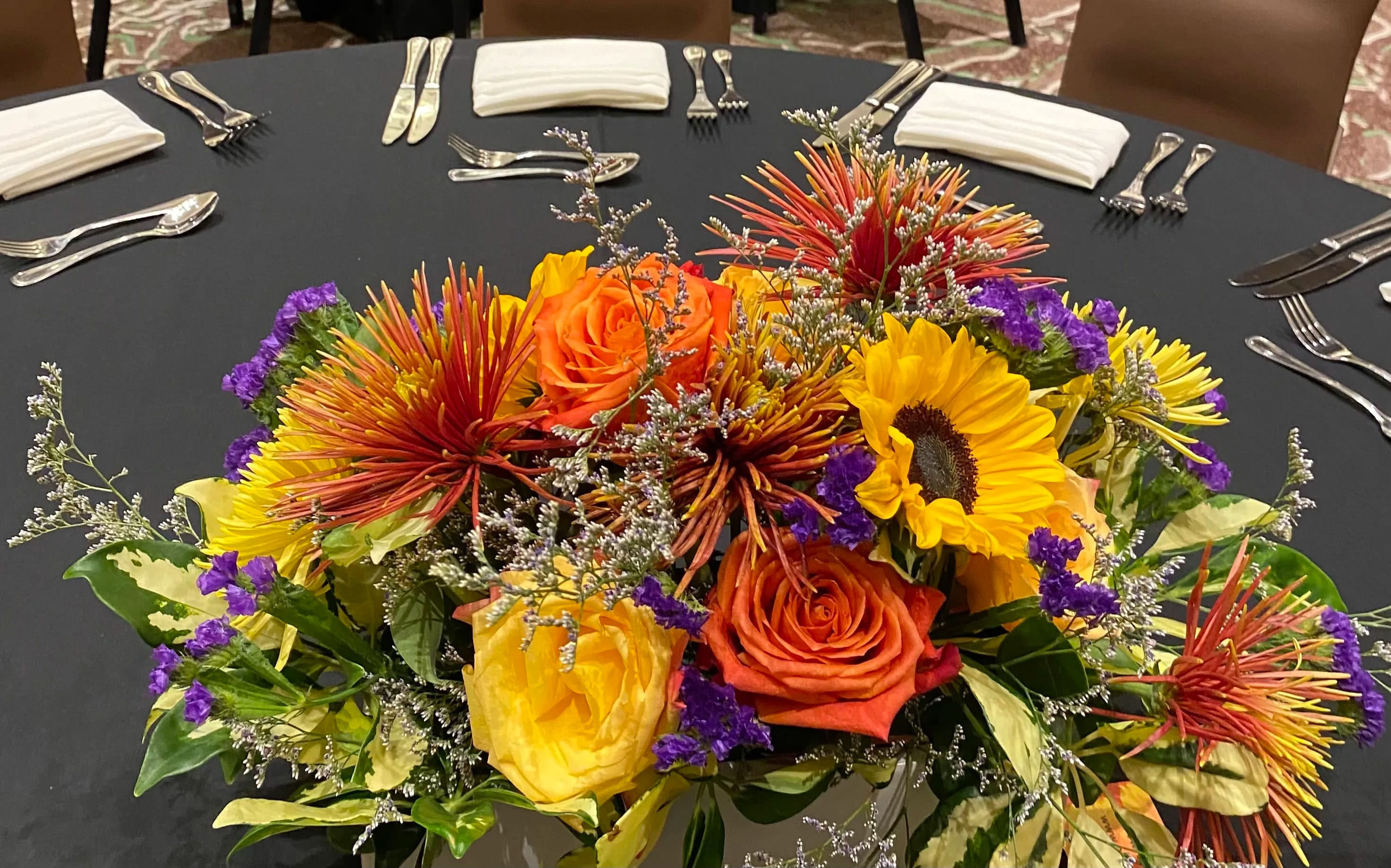 Bright mixed flower centerpiece with roses and sunflowers on a round table