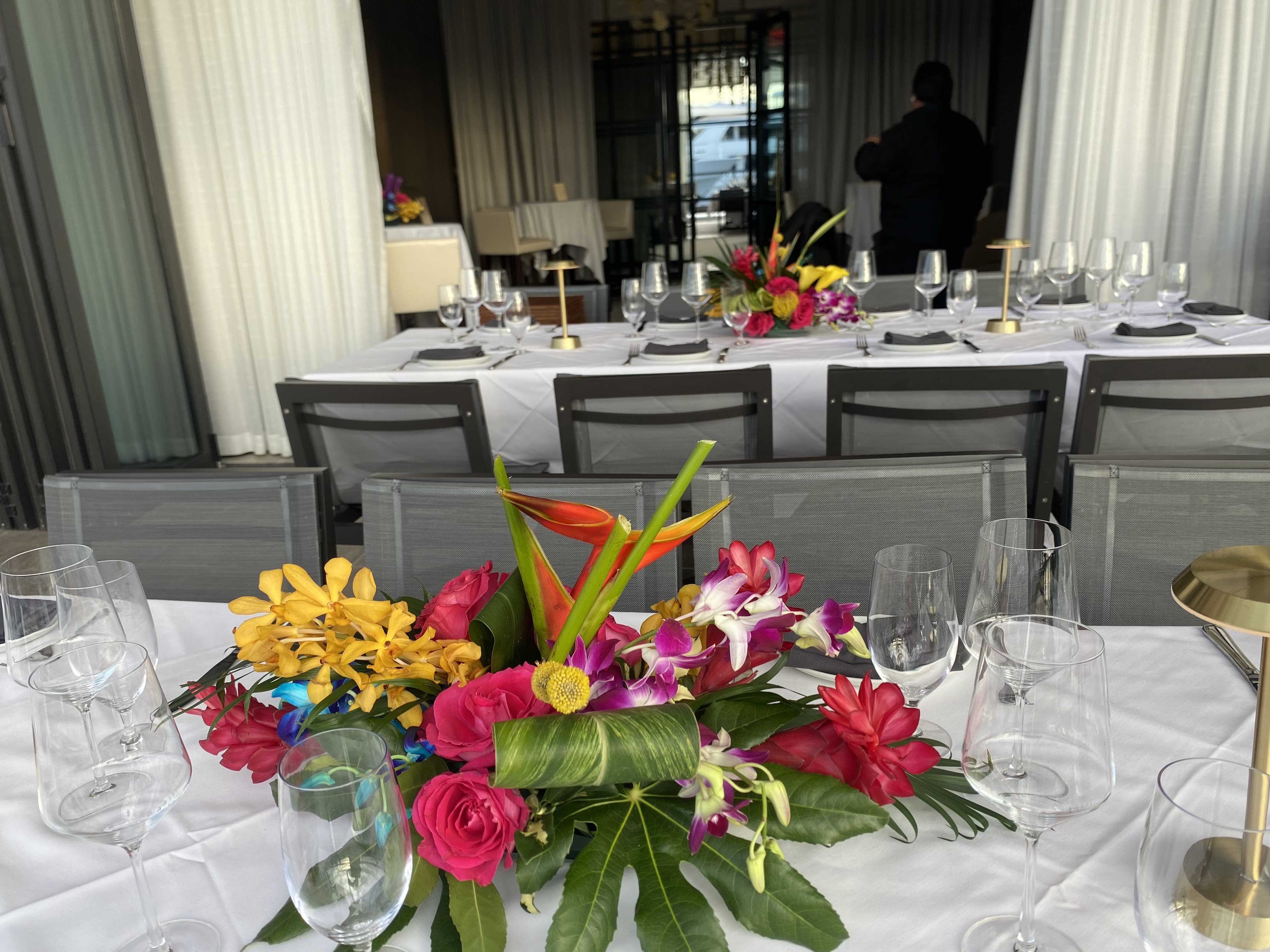 Bright tropical centerpiece with orchids, roses, and bird-of-paradise on a banquet table
