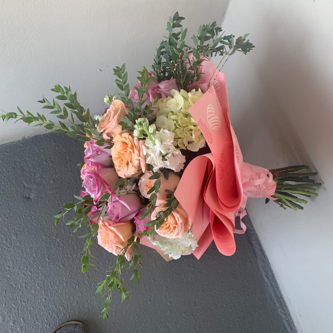 Bouquet of pink, peach, and white flowers wrapped in pink paper