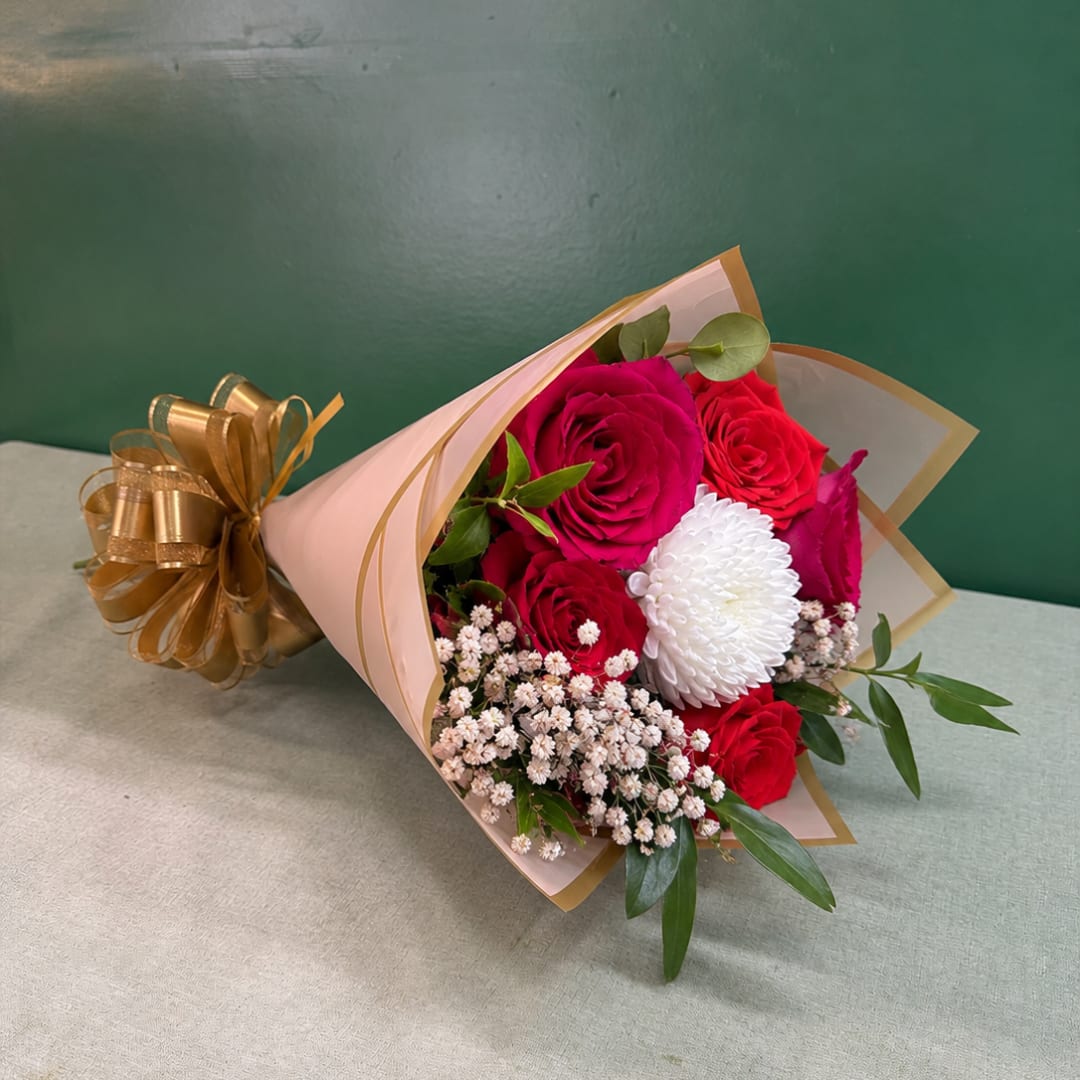 Bouquet of red and pink roses with a white chrysanthemum in pink wrap