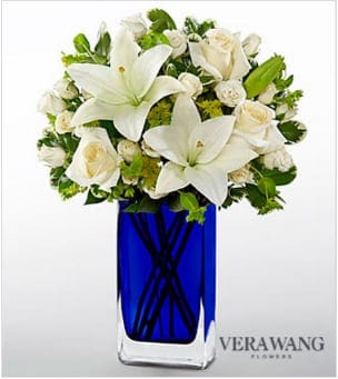 White lilies and roses arranged in a blue glass vase