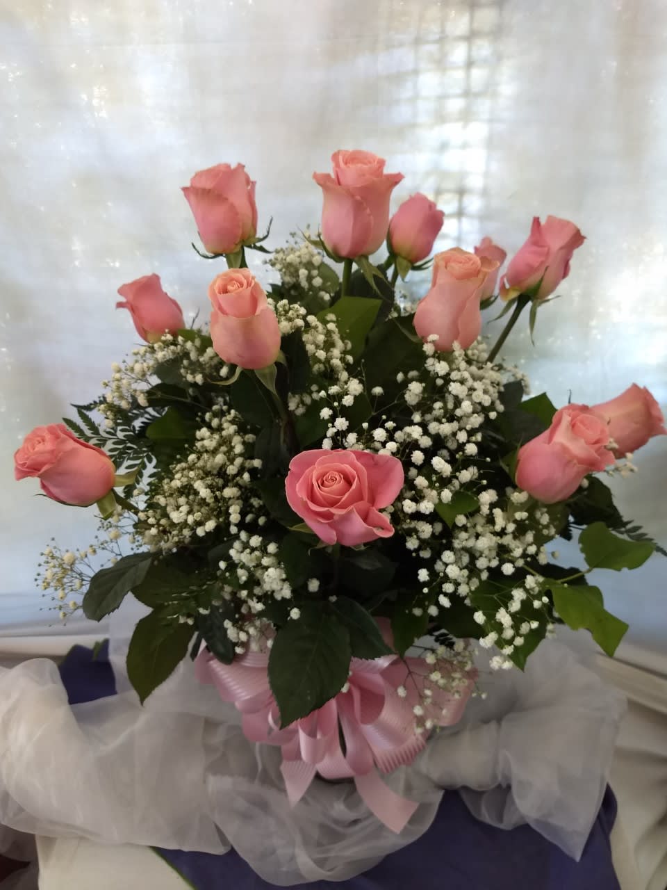 Pink roses arranged in a bouquet with baby's breath and a pink ribbon