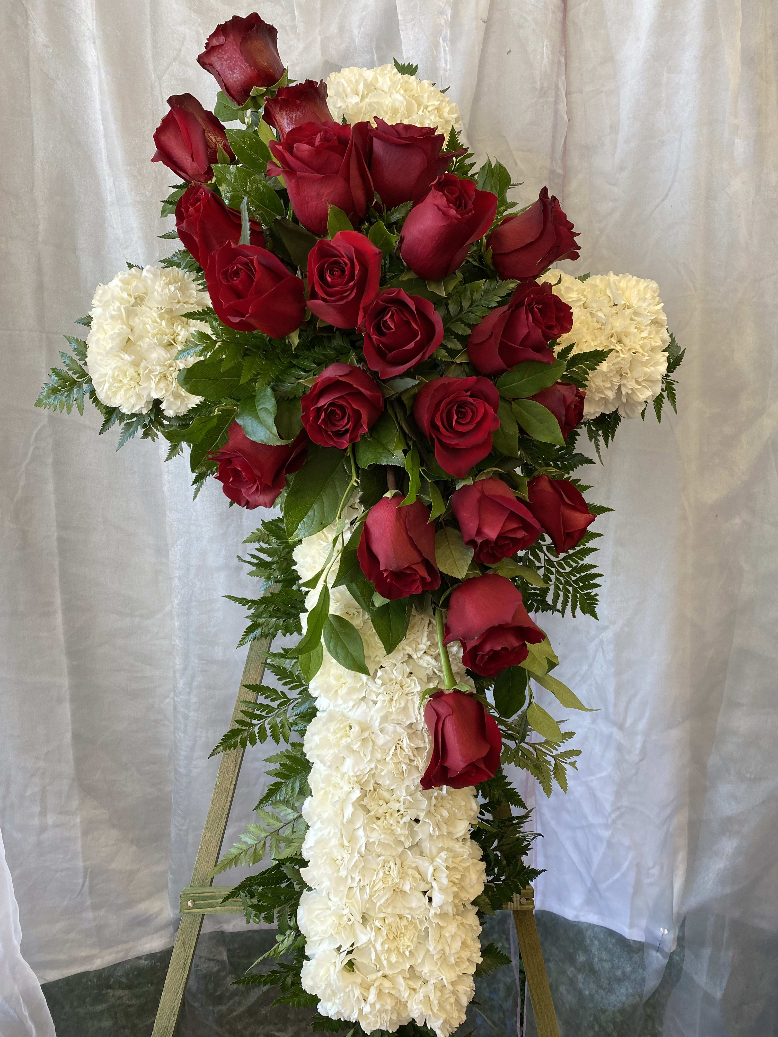 Cross-shaped floral tribute with red roses and white carnations