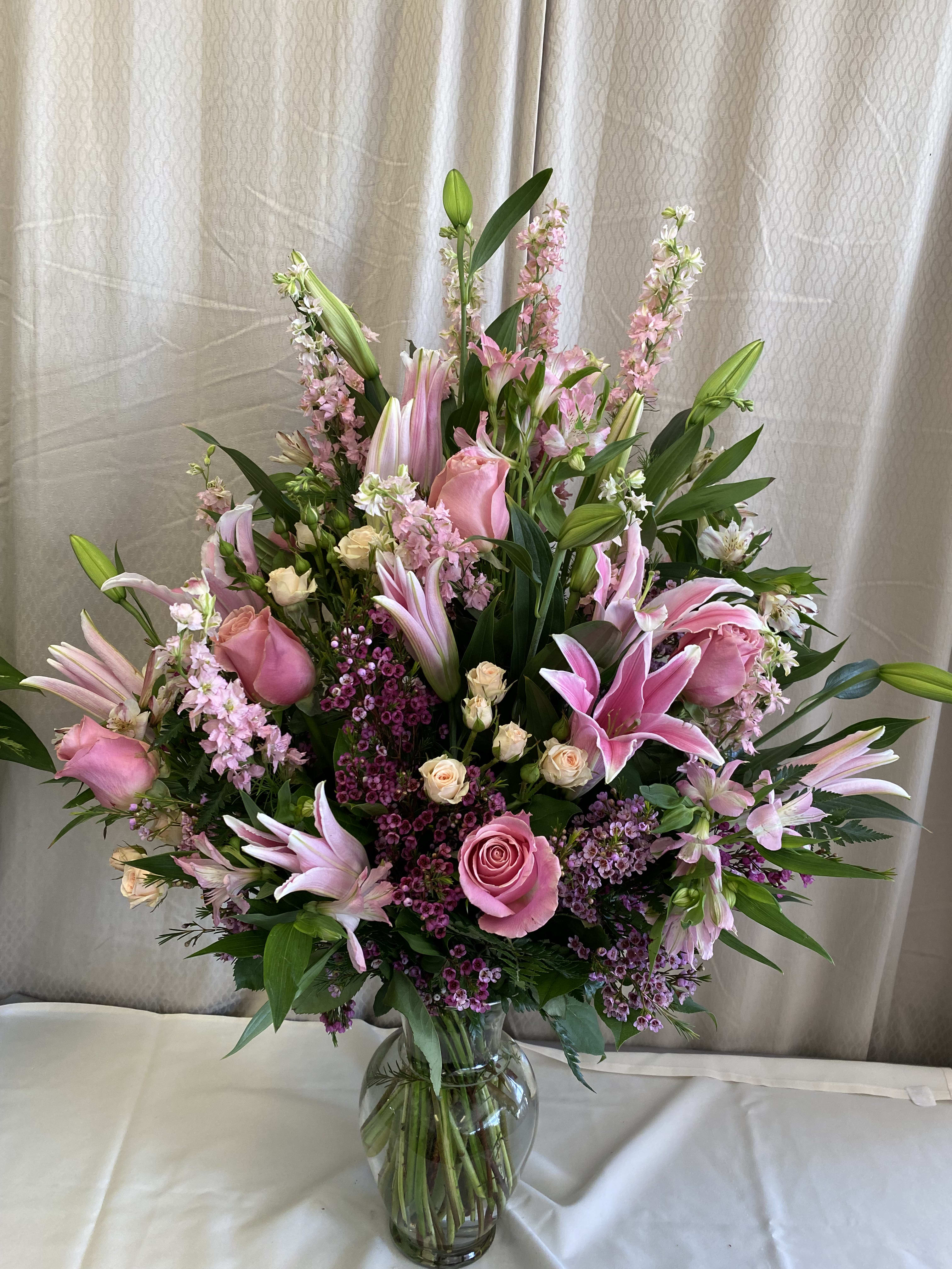 Pink lilies and roses arranged in a clear glass vase