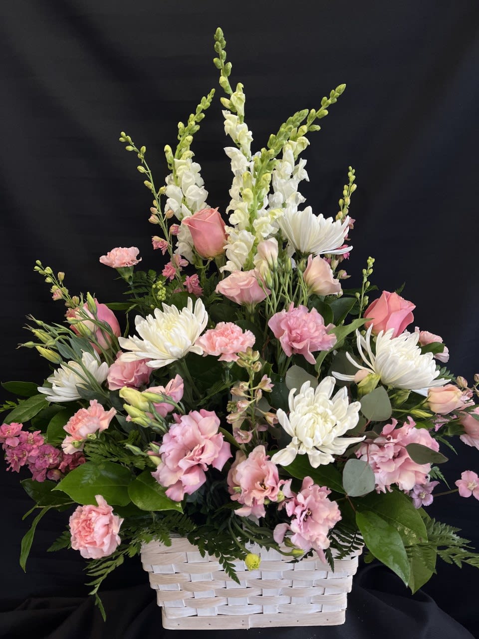 Pink and white mixed flower arrangement in a white basket