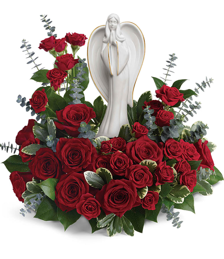 Forever Our Angel Bouquet - This peaceful porcelain angel sculpture, surrounded by radiant red roses and delicate greenery, is a touching tribute to a rich life. This radiant bouquet includes red roses, red spray roses, spiral eucalyptus, variegated pittosporum, and lemon leaf. Delivered with an Angel of Grace Keepsake. Approximately 16" W x 14 1/2" H