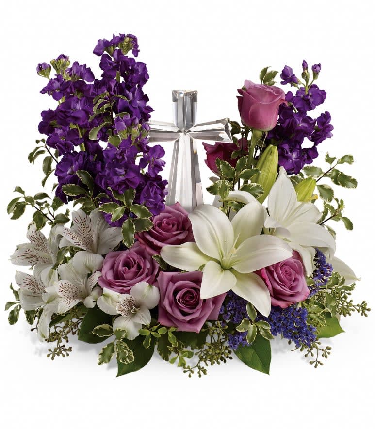 Grace And Majesty Bouquet - A bouquet to remember. This glorious garden of roses, lilies and alstroemeria surrounds a gleaming Crystal Cross. It's a radiant, reverent expression of faith that will be appreciated for years to come. Lavender roses, white asiatic lilies, white alstroemeria, purple stock and purple seafoam statice are arranged with fresh pitta negra, seeded eucalyptus and lemon leaf. Delivered with a Crystal Cross keepsake. Approximately 16 1/2" W x 14 3/4" H