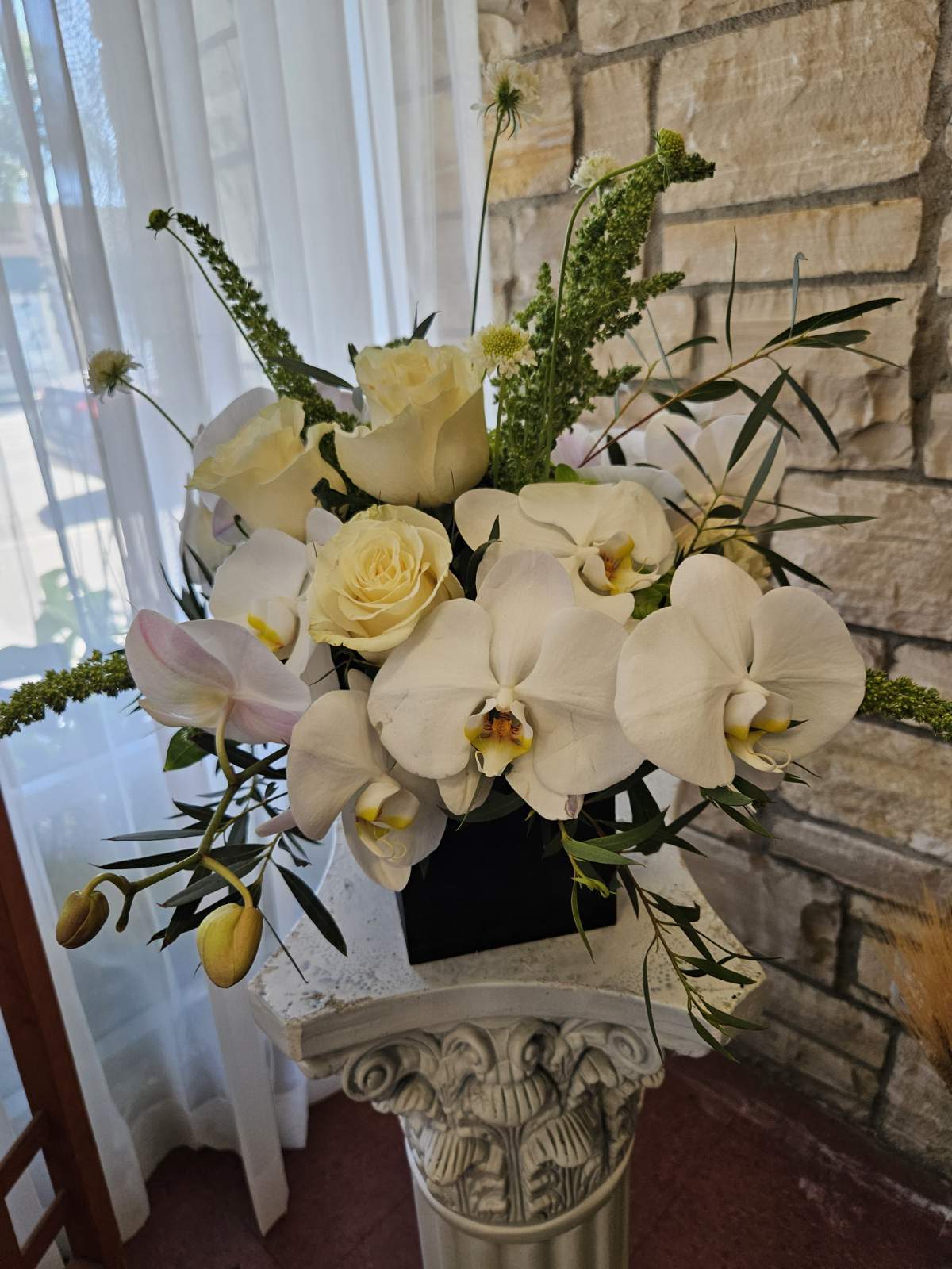 White orchids and cream roses arranged in a black vase