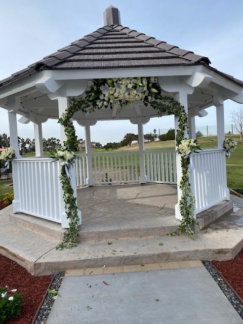 White floral garland decorates a gazebo with greenery and white blooms.