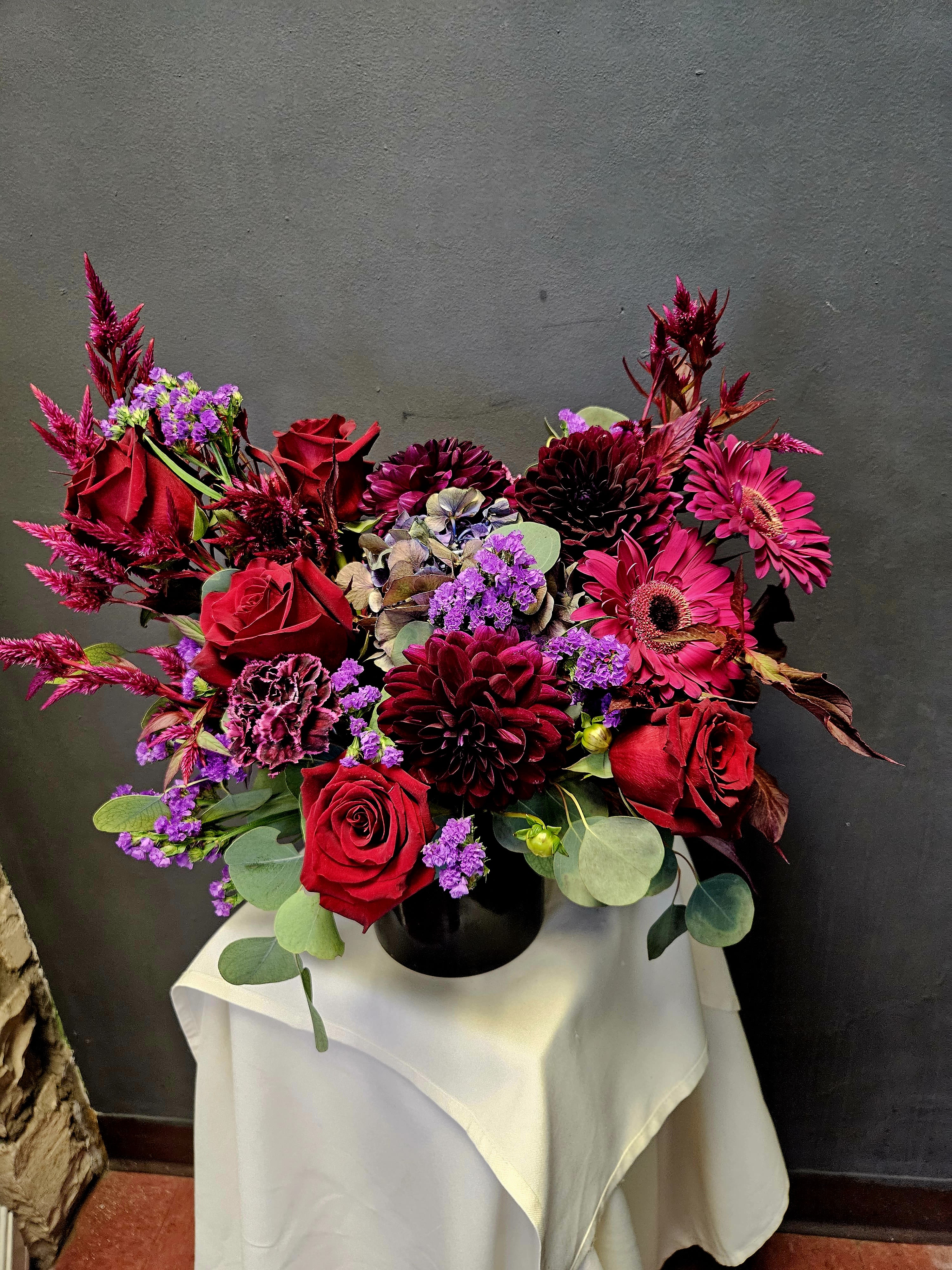 Red roses and magenta flowers arranged in a black vase
