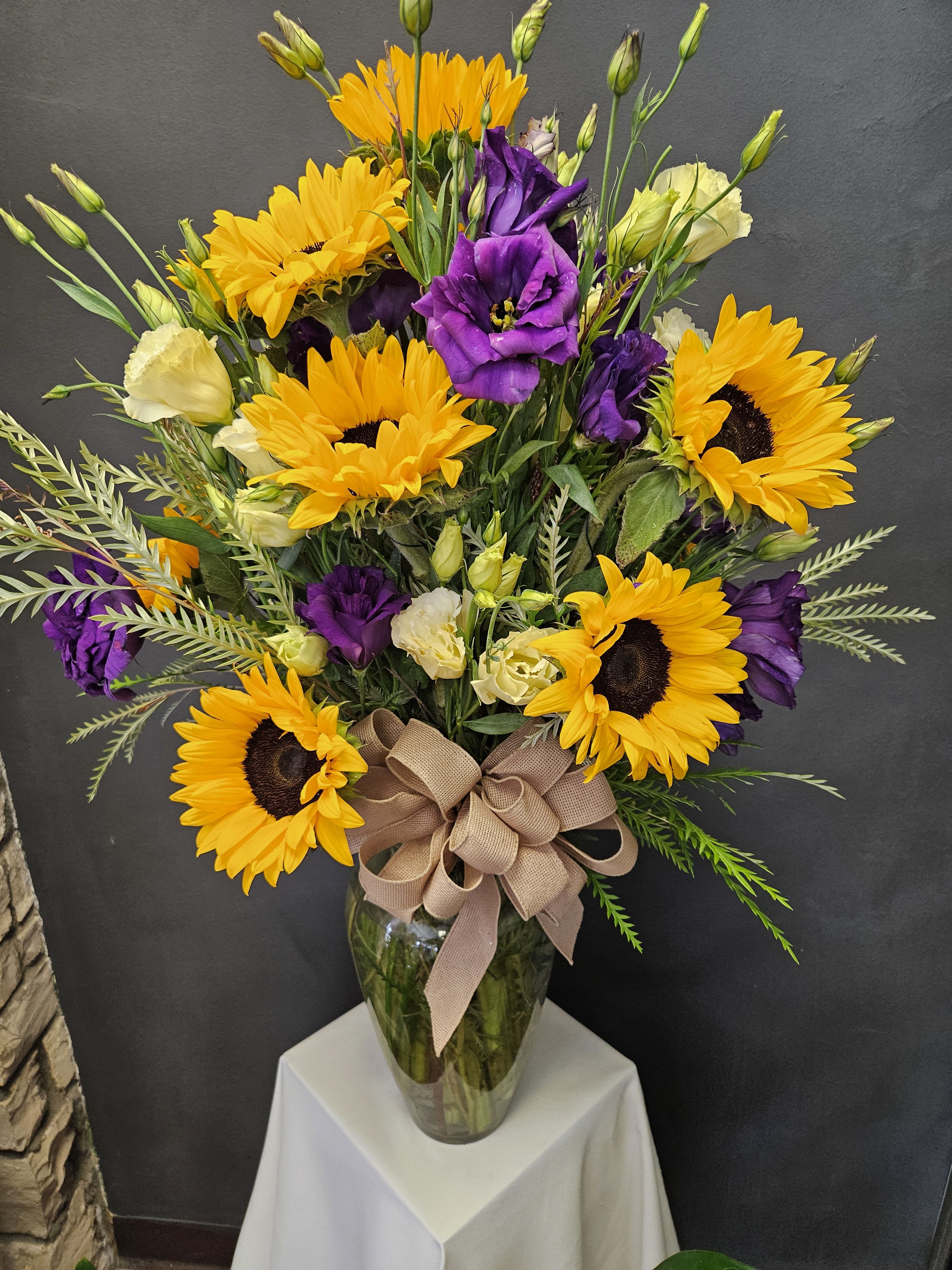 Bouquet of yellow sunflowers and purple lisianthus in a glass vase