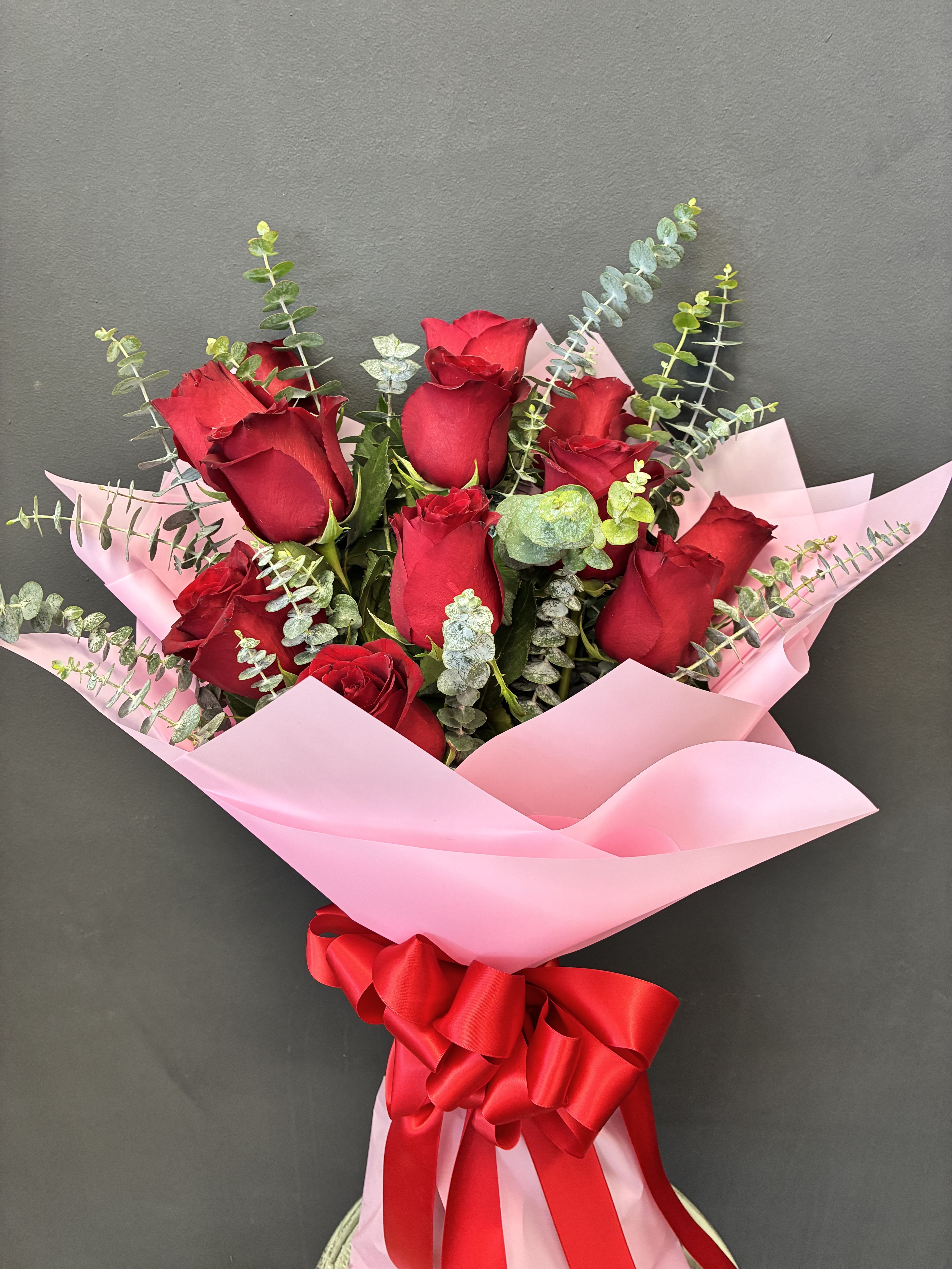 Bouquet of red roses wrapped in pink paper with a red ribbon