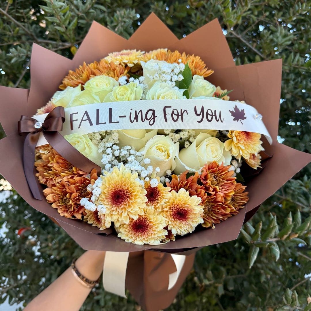 Bouquet of cream roses and orange chrysanthemums with a fall ribbon