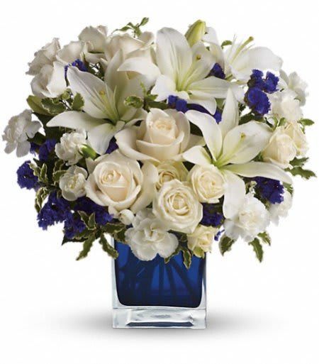 White lilies and roses arranged in a blue glass vase