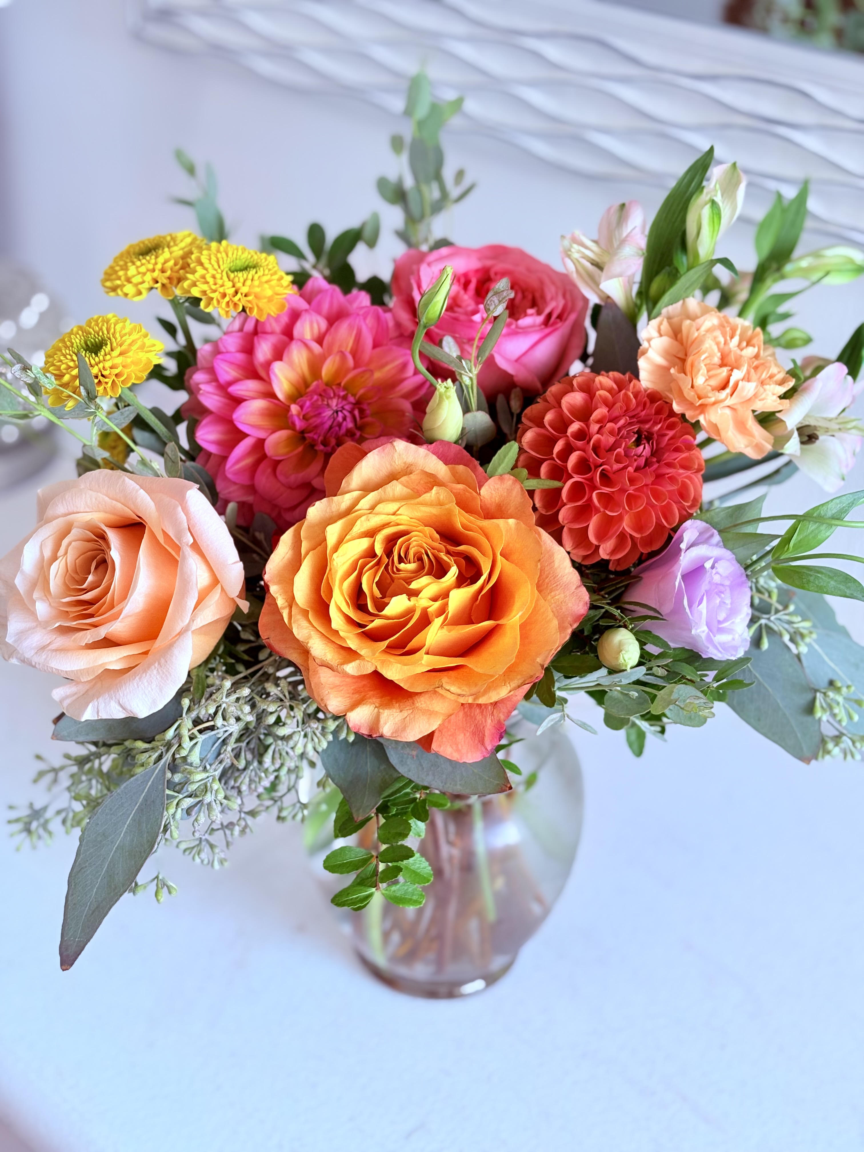 Mixed bouquet of roses, dahlias, and chrysanthemums in a glass vase