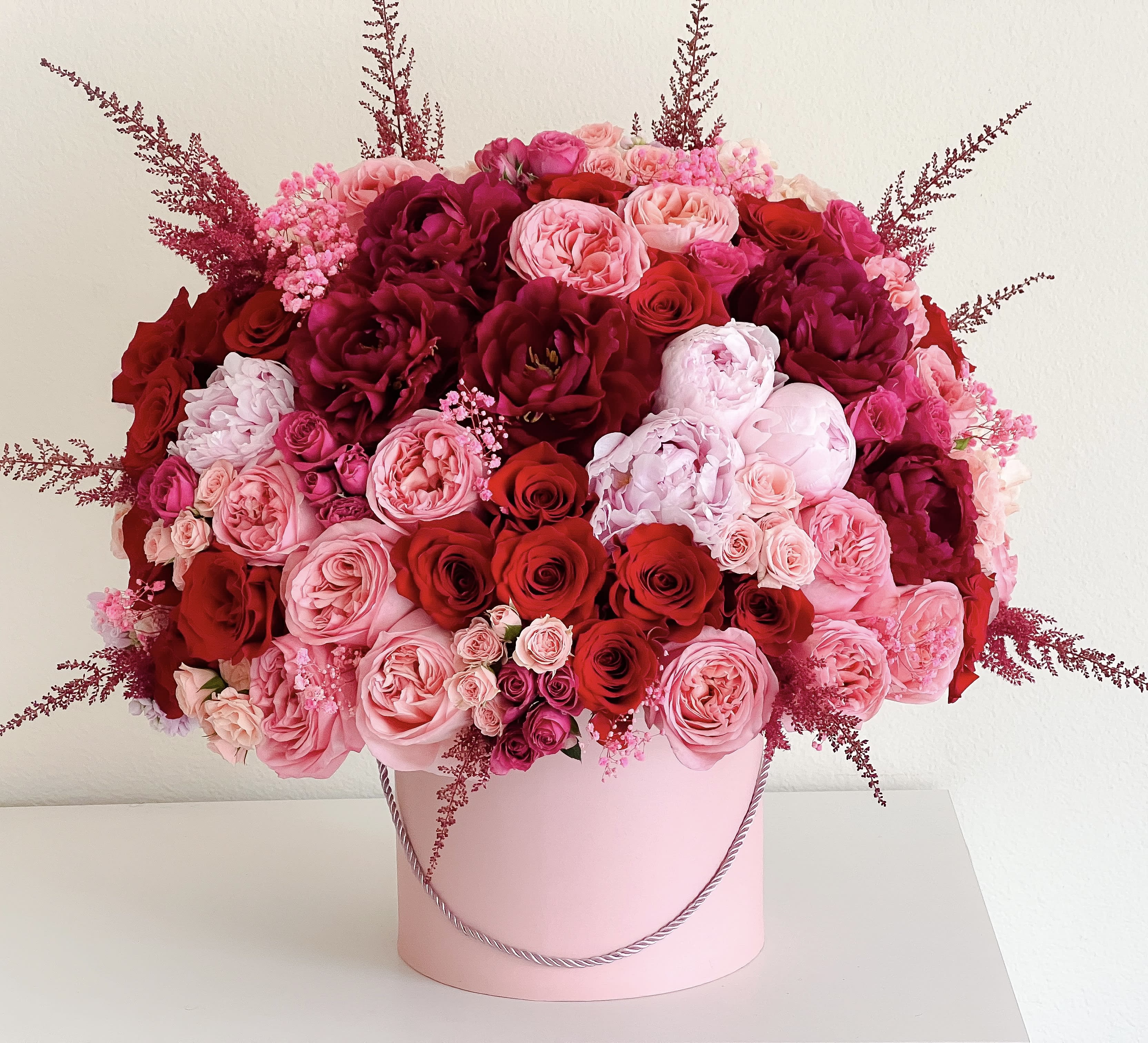Large pink and red rose arrangement in a pink hatbox