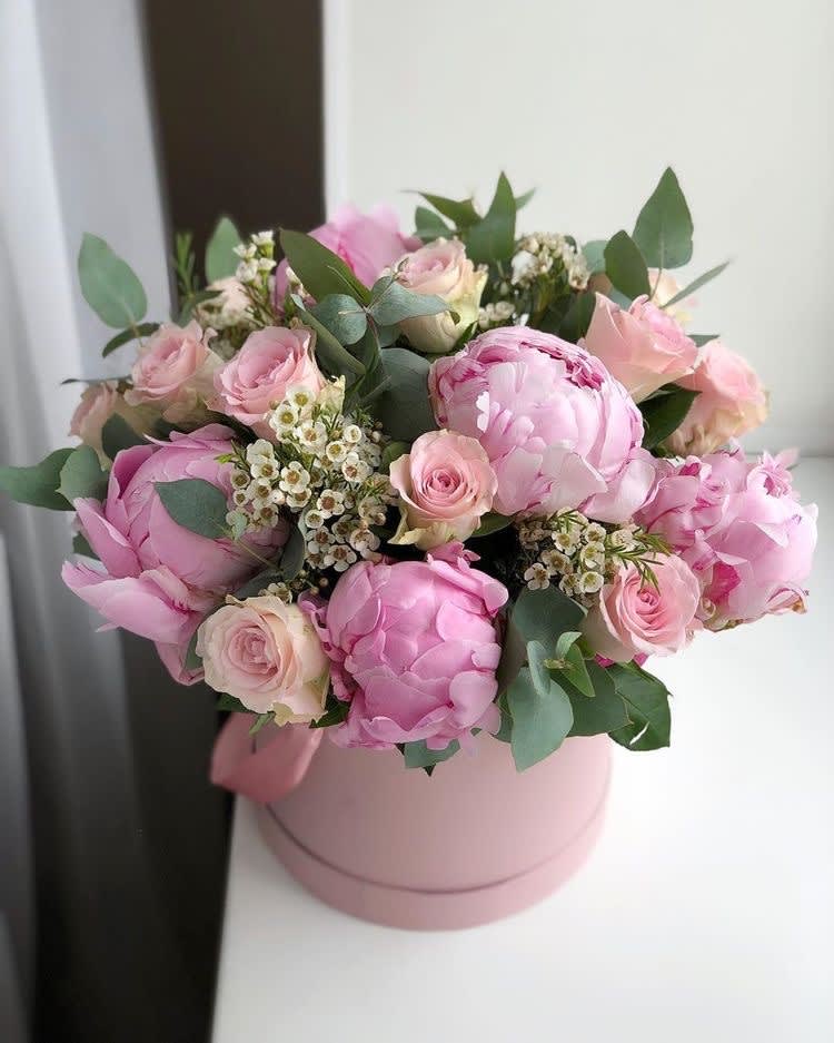 Pink peonies and roses arranged in a round pink box