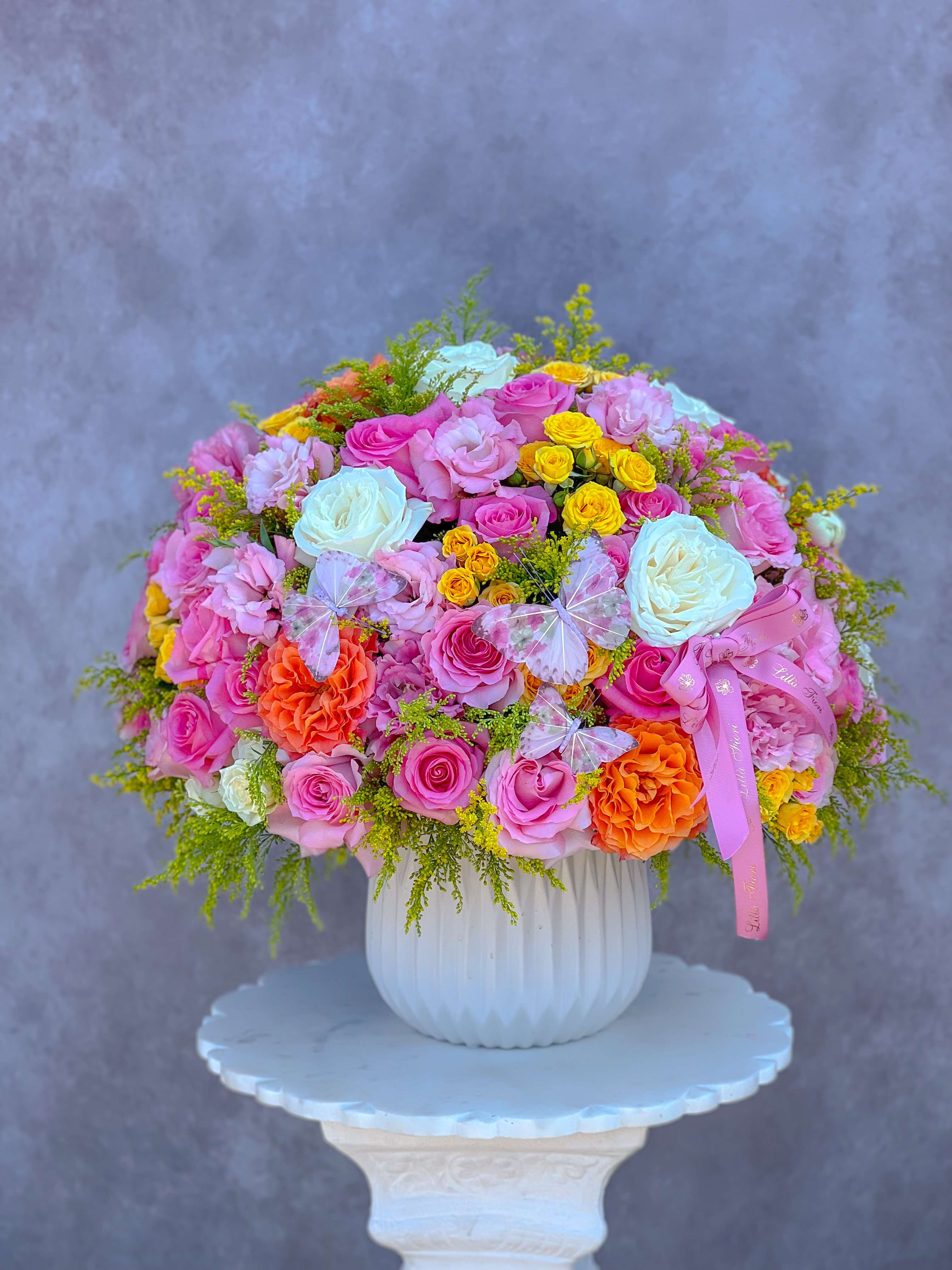 Large bouquet of pink, white, yellow, and orange roses in a white vase
